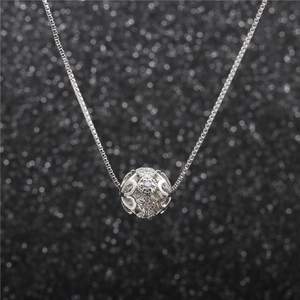 Macro shot of silver ball necklace with intricate filigree details and micro-set cubic zirconia