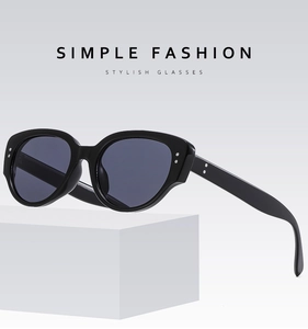 Detail of trendy black cat-eye sunglasses with silver rivets on a white geometric prop