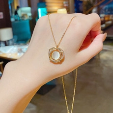 Dettaglio collana in oro con pendente rotondo, opale bianco e aureola di zirconi