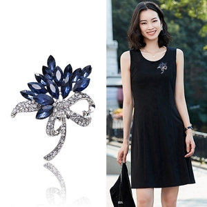Elegant flower brooch with dark blue gems and sparkling bow design shown on model