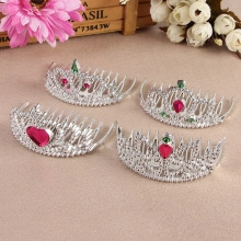 Close-up of four silver princess crowns with pink heart gems for children hair styling