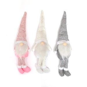 Detail of three knitted Christmas gnomes with long legs and sequined hats in soft tones