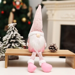 Pink Nordic Christmas gnome with long legs sitting on a wooden bench for holiday home decor