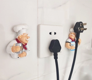 Close-up of cute chef plug hooks for power cord organization on marble tile wall