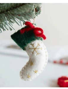 Detail of wool felt Christmas stocking ornament with gold snowflake on pine branch