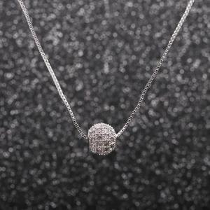 Gros plan d'un collier en argent avec pendentif sphérique pavé de zircons sur chaîne maille