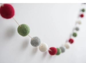 Macro detail of Nordic Christmas wool felt ball garland in red green gray and white