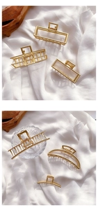 Close-up of elegant gold metal hair claws in geometric and mesh designs on silk