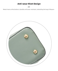 Detail view of anti-wear metal studs and stitching on light green leather bag base