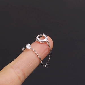 Detail of silver chain earring with zircon studs and a connector chain on fingers