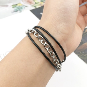 Nahaufnahme eines mehrlagigen Leder- und Silberkettenarmbands am Handgelenk in modischem Stil