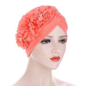 Vue détaillée de trois fleurs 3D en tissu avec perles et strass sur un bonnet turban