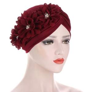 Détail d'un turban rouge avec trois fleurs appliquées ornées de perles et de strass