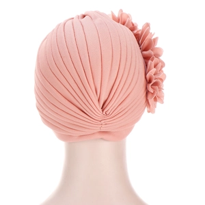 Détail d'un turban rose avec grande fleur 3D et tissu élastique à texture plissée