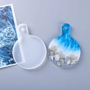 Detailed view of round resin tray mold and finished ocean-themed art piece with shells