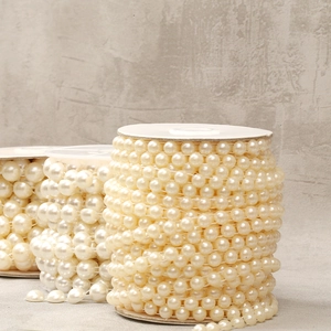 Detail of cream white ABS imitation pearl bead chain on spool for DIY crafts and sewing