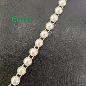 Detailed view of 6mm white ABS half round pearl beads on black leather surface