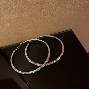 Elegant silver hoop earrings featuring sparkling rhinestones on a sleek black background