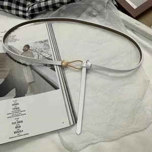 Close-up of white skinny leather belt with gold buckle on fashion magazine background