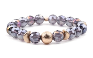 Macro shot of faceted grey crystal beads with a rose gold frosted accent bead on white