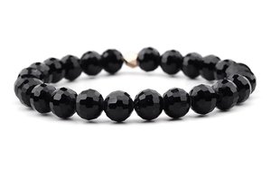 Detail of faceted black beads and a faceted golden metal bead on elastic bracelet
