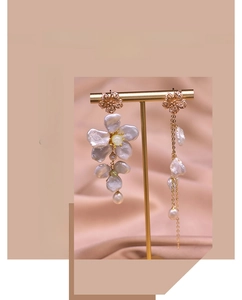Detail of asymmetric baroque pearl drop earrings with elegant golden floral tassels