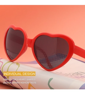 Close-up of stylish red heart-shaped sunglasses with dark lenses on a fashion magazine