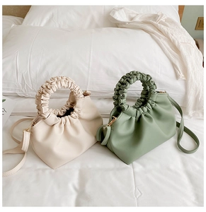 Detail of gathered pleats and soft PU leather texture on cream and sage green handbags