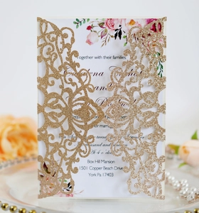 Macro detail of laser cut gold glitter wedding invitation with floral insert card