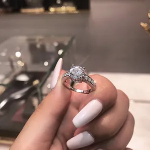 Close-up of silver ring featuring a four-claw set round zircon held by hand for display