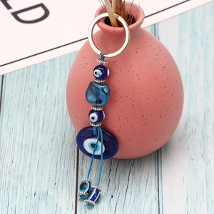 Detail of blue evil eye keychain with glass beads and metallic ring on wooden background