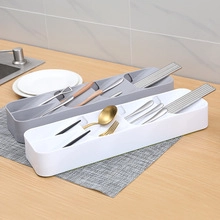 Kitchen drawer organizer for cutlery in white and gray plastic on a wooden countertop