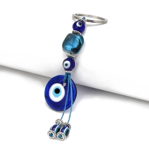 Close-up of blue glass Evil Eye pendant with intricate woven cord and metal keychain detail