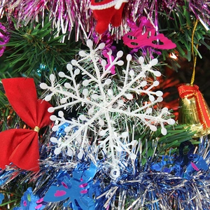 White glittering snowflake ornament hanging on a decorated Christmas tree with festive ribbons