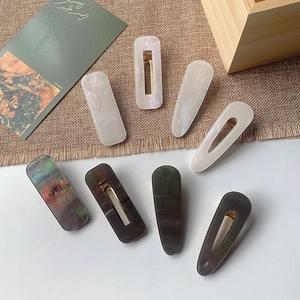 Detailed view of colorful acrylic hair clips with marble texture and golden metal duckbill clips