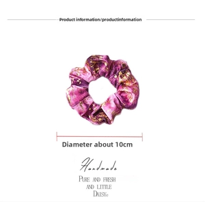Detail of a handmade dark purple velvet scrunchie with gold foil speckles and 10cm diameter