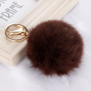 Detailed view of fluffy dark brown faux fur pompom keychain with golden metal clasp