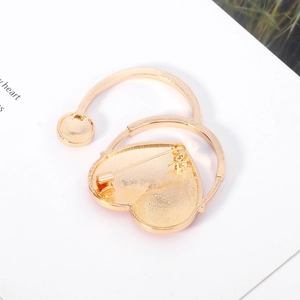 Broche stéthoscope cœur dorée avec fermoir de sécurité sur fond blanc épuré