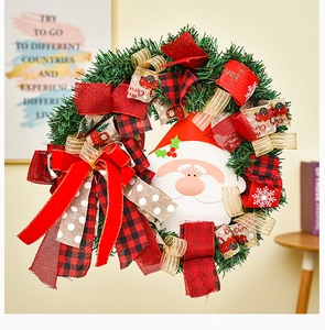 Detail of Christmas wreath with Santa Claus icon and red plaid festive ribbon bows