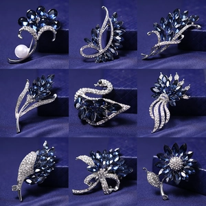 Collection of nine dark blue crystal and silver alloy brooches in floral and swan shapes