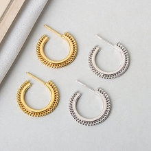 Detailed macro view of gold and silver metallic woven texture hoop earrings
