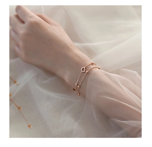 Detailed close-up of rose gold double-layer bracelet with horseshoe pendant and beads