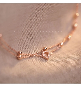 Macro shot of rose gold double-layer chain bracelet featuring a diamond-encrusted letter D