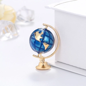 Elegant blue globe brooch with golden accents shown on a minimalist modern display