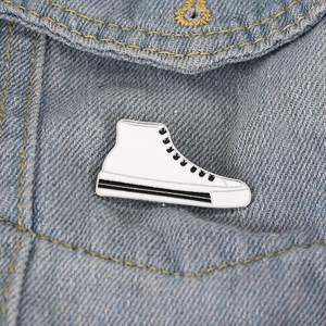 Detail of white high-top sneaker enamel pin on light blue denim jacket texture