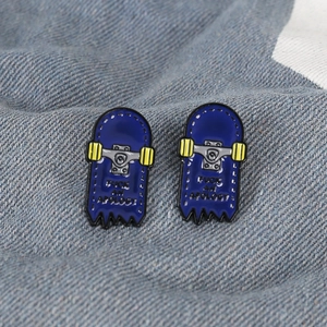 Detail of blue skateboard enamel pins with yellow wheels on denim fabric texture