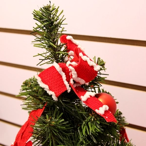 Mini albero di Natale con fiocchi di velluto rosso e palline opache su rami di pino ghiacciati