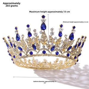Detail view of Baroque gold crown with blue crystals and white rhinestones on white background