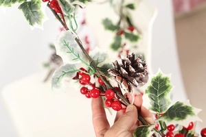 Gros plan d'une guirlande de Noël avec des baies rouges, des feuilles blanches et une pomme de pin