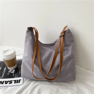 Detail of purple nylon tote bag with brown leather strap and high-quality metallic buckle